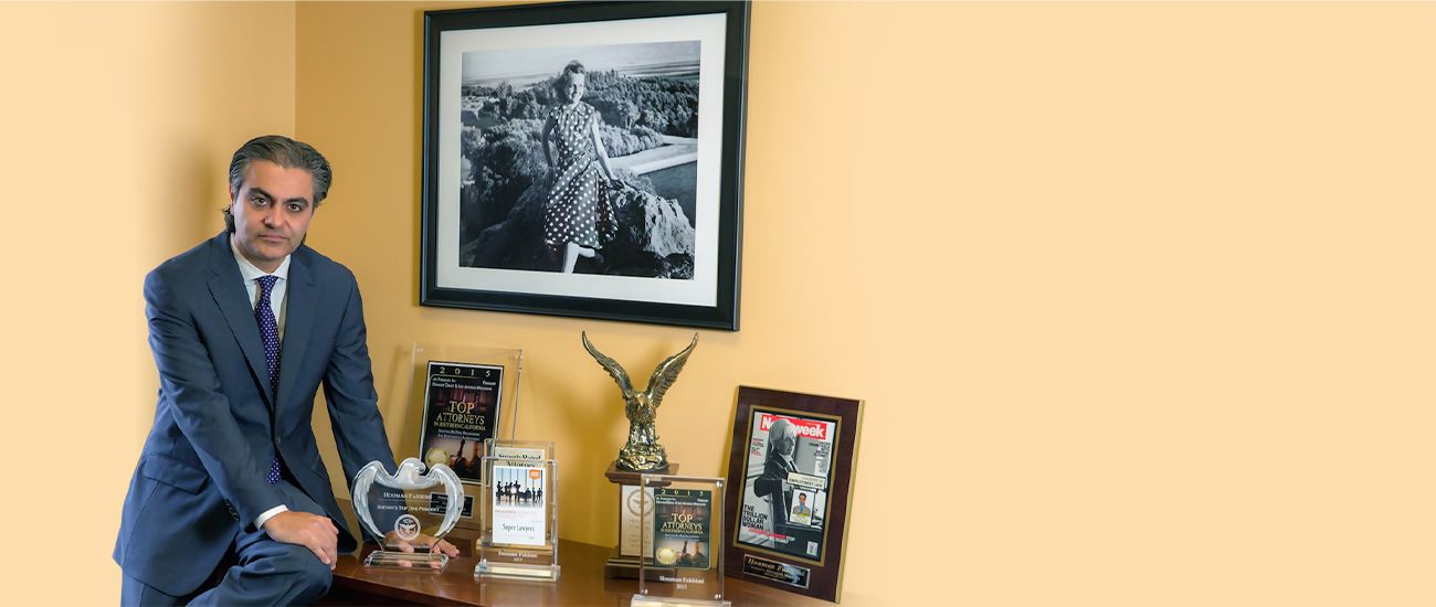 Houman Fakhimi sits at a desk, next to some of his prizes as an attorney