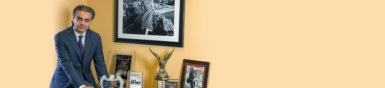 Houman Fakhimi sits at a desk, next to some of his prizes as an attorney